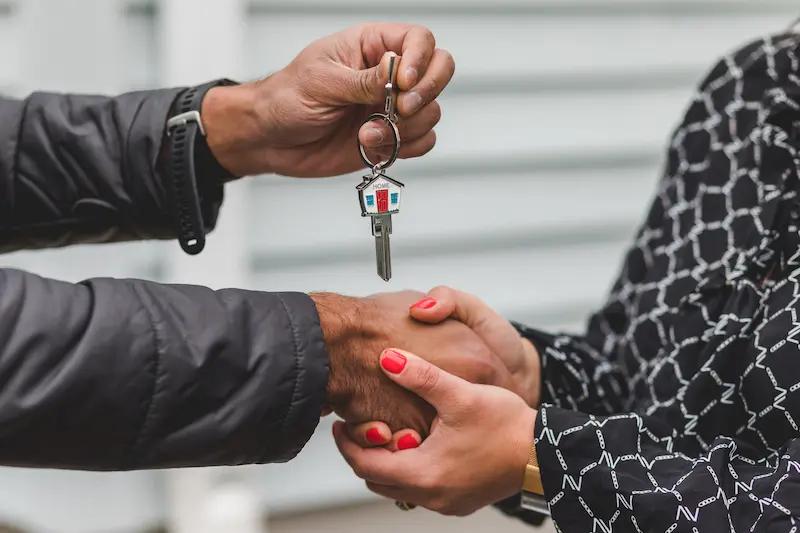 Persona entregando las llaves de una vivienda nueva como símbolo de compra o arriendo.