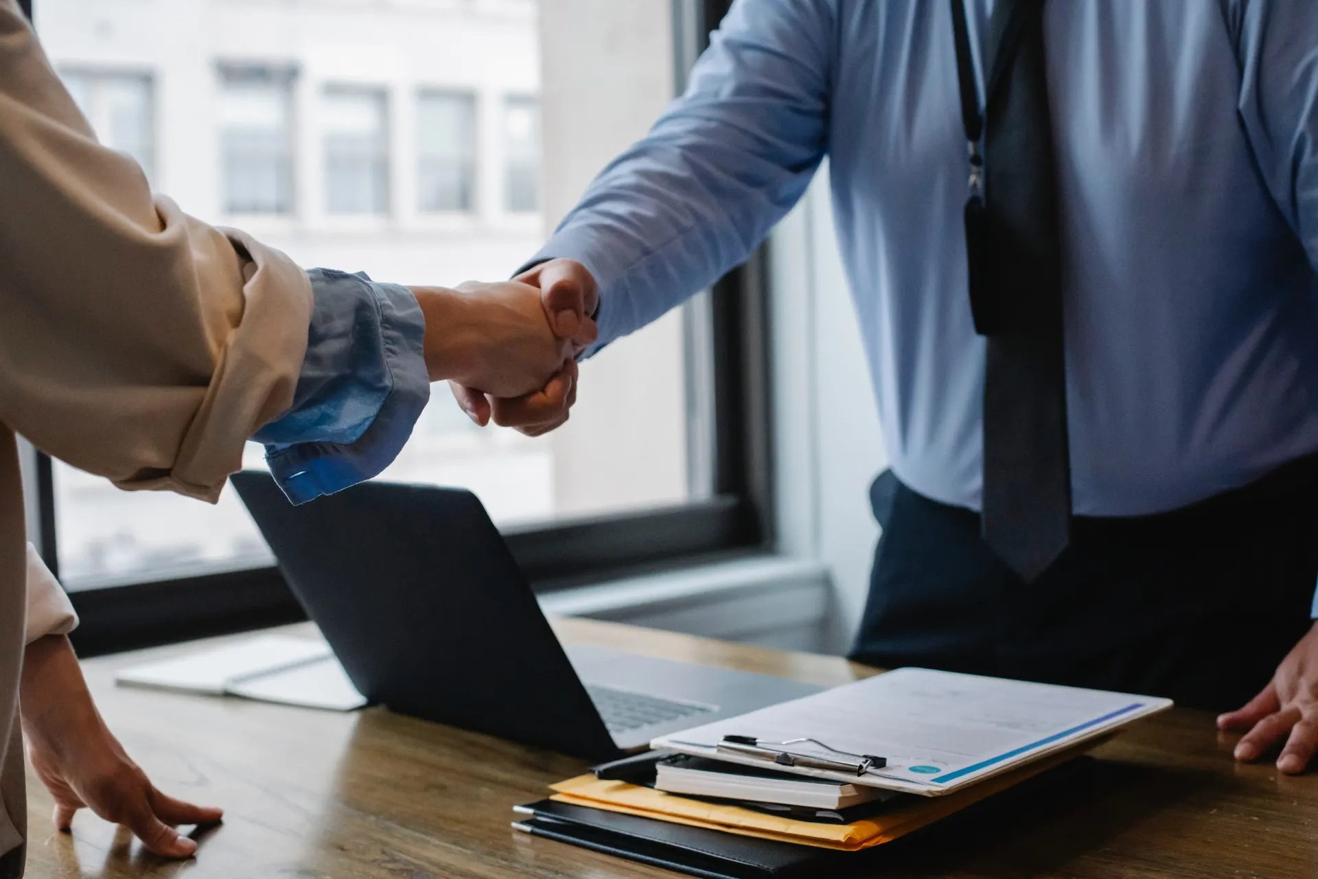 Ejecutivo y cliente cerrando un acuerdo financiero con un apret贸n de manos en una oficina