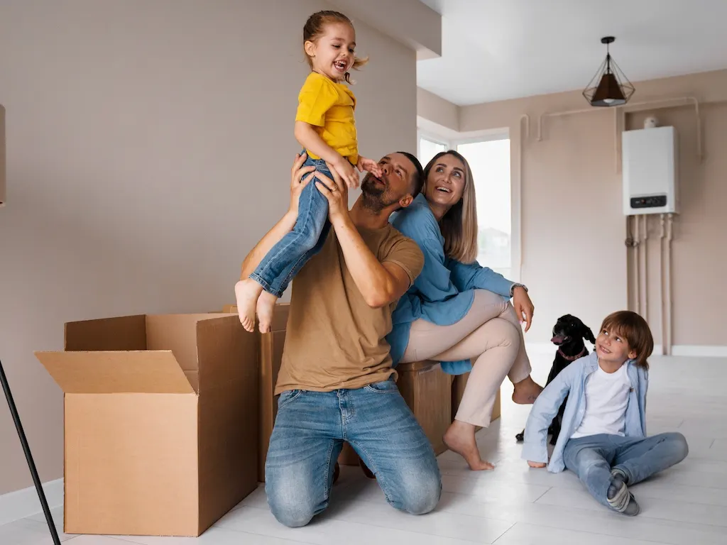 Familia feliz con dos ni帽os y un perro en su nuevo hogar, rodeados de cajas de mudanza