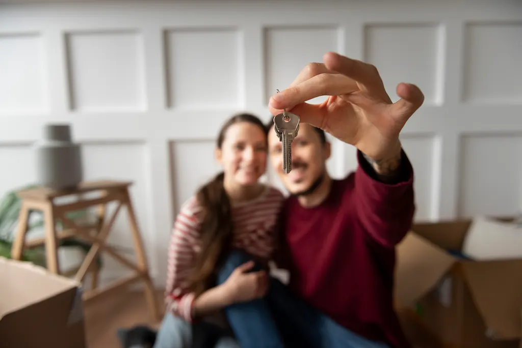 Pareja sentada en su nuevo hogar mientras sostienen una llave